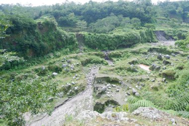 Merapi dağının yamacında yeşil bitkilerle kaplanmış eski kum ocağı.