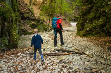 Two backpackers (a woman with a little son) are walking along a creek in a canyon of the Slovak Paradise National Park, Slovakia.