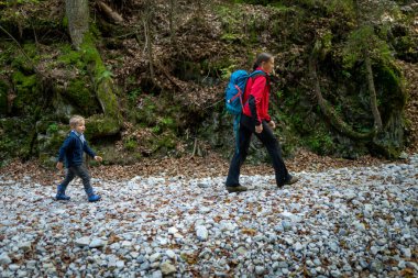 Two backpackers (a woman with a little son) are walking along a creek in a canyon of the Slovak Paradise National Park, Slovakia.