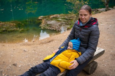 Anne ve oğlu güzel bir turkuaz gölün kenarındaki bankta dinleniyorlar. Polonya dağları