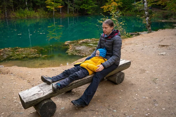 Mom and son are resting on a bench by a beautiful turquoise lake. Polish mountains