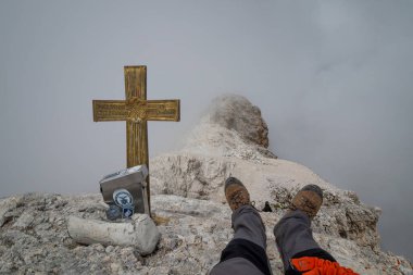 Cima di Mezzo 'nun (3154 m) tepesinden bulutlar tarafından görülemeyen görüntü. Turist, yanındaki kuşla dinleniyor..