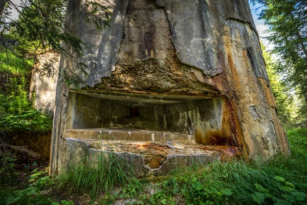 Abandoned, destoyed concrete bunker with embrasure in summer forest.Entrance to the bunker. Dolomites, Italy