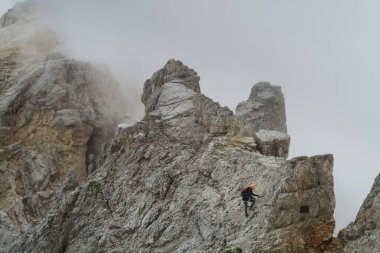 Alplerdeki Ferrata patikasında ekipmanlı bir turist. Dolomitler, İtalya