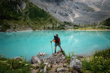 İtalyan Dolomitleri 'ndeki güzel Lago di Sorapis gölünün arka planında poz veren bir turist.