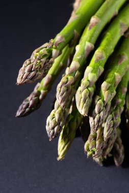 Koyu arka plan üzerinde taze yeşil kuşkonmaz