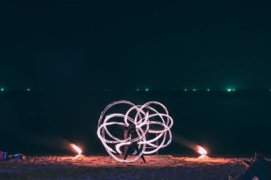 Yaz tatili konsepti, Koh Samui, Tayland 'da gece partisinde deniz üzerinde su yansıtan çelik yün ören adam.