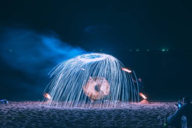 Yaz tatili konsepti, Koh Samui, Tayland 'da gece partisinde deniz üzerinde su yansıtan çelik yün ören adam.