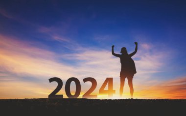 Yeni yıl 2024 seyahat konsepti, Siluet mutlu gezgin kadın gün batımında gökyüzü arka planına sahip neşeli ve kollu