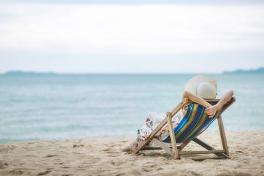 Yaz tatili konsepti, şapkalı ve elbiseli gezgin Asyalı kadın Pattaya, Chon Buri, Tayland 'da sandalye plajında dinleniyor.