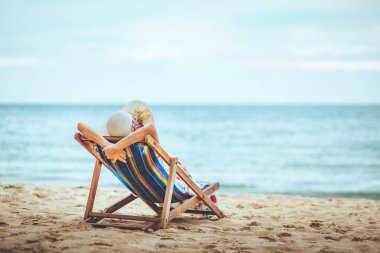 Yaz tatili konsepti, şapkalı ve elbiseli gezgin Asyalı kadın Pattaya, Chon Buri, Tayland 'da sandalye plajında dinleniyor.
