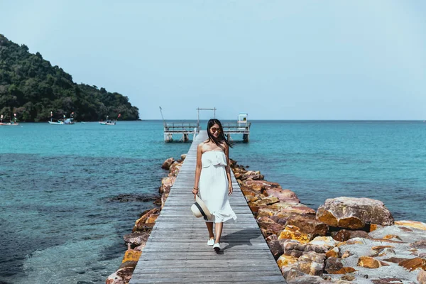 Summer vacations concept, Happy travel woman with white dress relax and walk on wooden bridge in tropical beach, Thailand