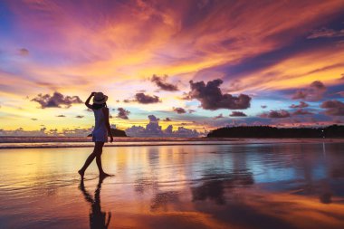 Yaz tatili konsepti, şapkalı Asyalı gezgin kadın Phuket, Tayland 'da gün batımında Kata plajını geziyor.
