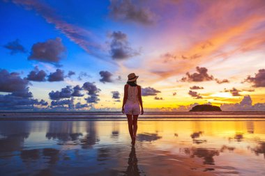 Yaz tatili konsepti, şapkalı Asyalı gezgin kadın Phuket, Tayland 'da gün batımında Kata plajını geziyor.