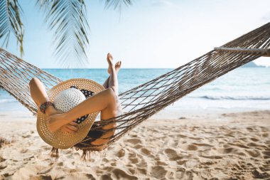 Yaz tatili konsepti, beyaz bikinili mutlu Asyalı kadın Koh mak, Tayland 'da hamakta dinleniyor.
