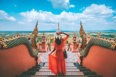 Happy traveler asian woman with dress travel in Wat Phra That Doi Phra Chan temple, Lampang, Thailand clipart