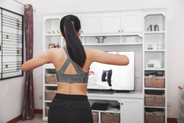 Evde sağlıklı egzersiz konsepti, Asyalı fit kadın evde kalıp televizyonda spor eğitimi veriyor, covid-19 salgınının yeni normal hayatı.