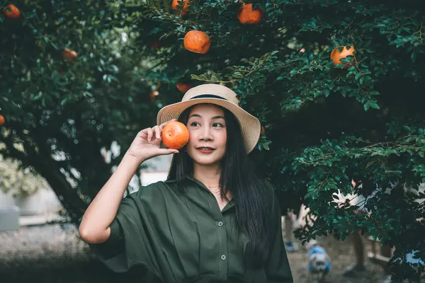 Portrait of Happy traveler asian woman with orange holding hand relax in orchard and cafe at Thailand