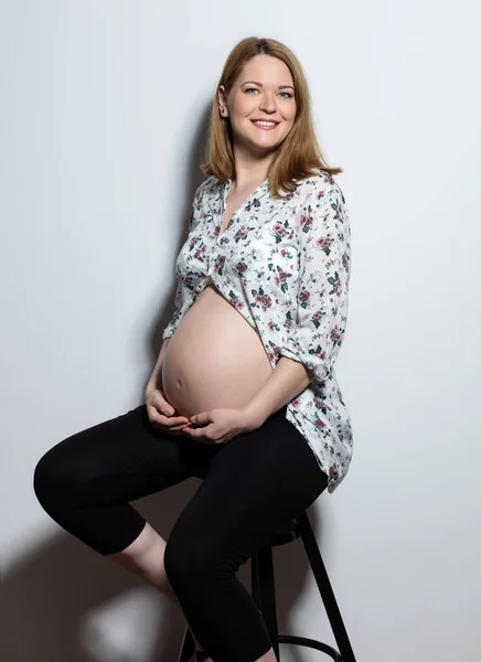 Portret Pięknej Kobiety Ciąży Siedzącej Przy Białej Ścianie — Zdjęcie stockowe