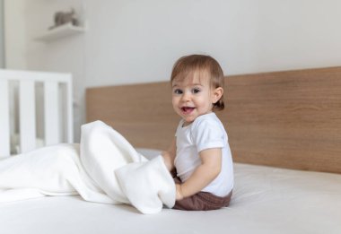 12 aylık sevimli bir çocuk battaniyeyle oynuyor.