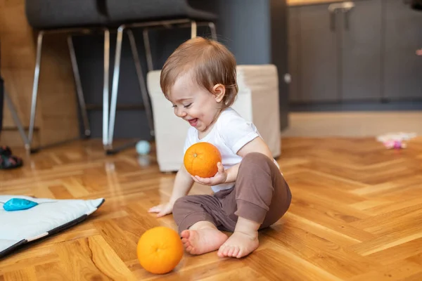 Adorable one year old child playing with orange, shallow depth of field