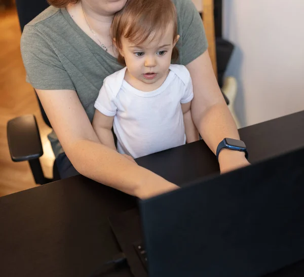 working mother with child and laptop computer at home office