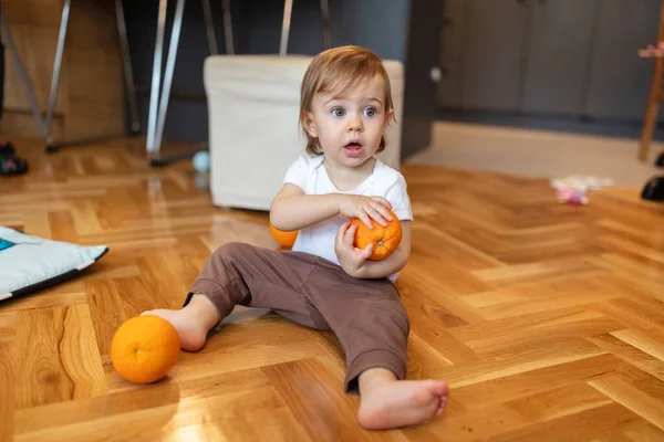 Liebenswertes Einjähriges Kind Das Mit Orangefarbener Flacher Schärfentiefe Spielt lizenzfreie Stockbilder
