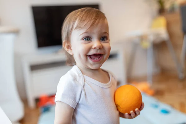 Liebenswertes Einjähriges Kind Das Mit Orangefarbener Flacher Schärfentiefe Spielt lizenzfreie Stockfotos