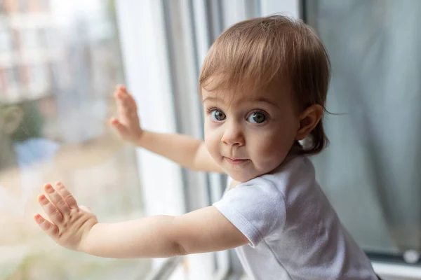 Porträt Eines Entzückenden Einjährigen Kindes Das Durch Das Fenster Blickt lizenzfreie Stockfotos
