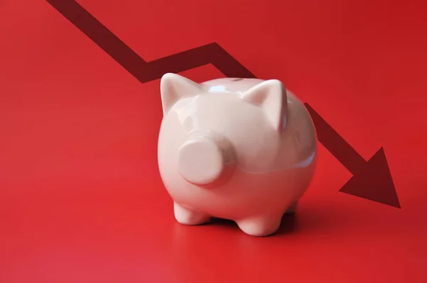 A piggy bank on a red background and a down arrow behind it. Symbol of bankruptcy