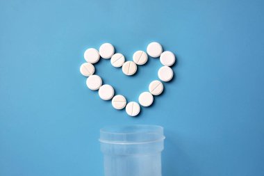 Heart-shaped pills on a blue background