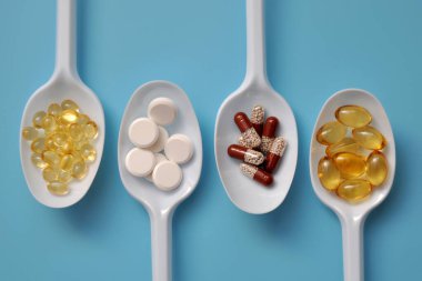 Tablets, capsules, dietary supplements, vitamins on white spoons. Medical background with pills clipart