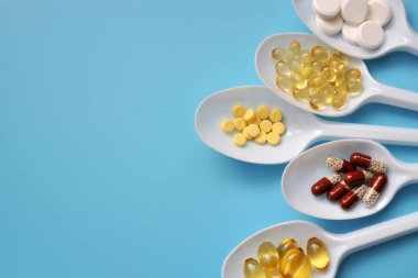 Tabletler, kapsüller, beslenme takviyeleri, beyaz kaşıklarda vitaminler. İlaçlı tıbbi geçmiş