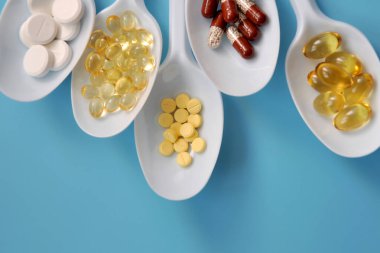 Tabletler, kapsüller, beslenme takviyeleri, beyaz kaşıklarda vitaminler. İlaçlı tıbbi geçmiş