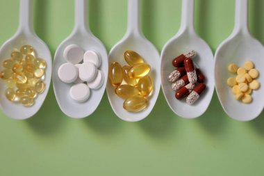 Tabletler, kapsüller, beslenme takviyeleri, beyaz kaşıklarda vitaminler. İlaçlı tıbbi geçmiş