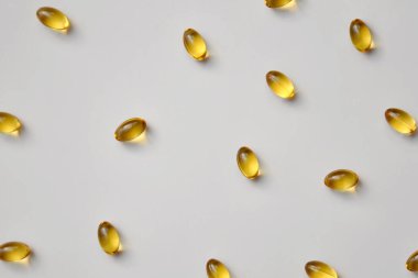 Sarı haplar, kapsüller, açık gri arka planda vitaminler, tıbbi geçmiş