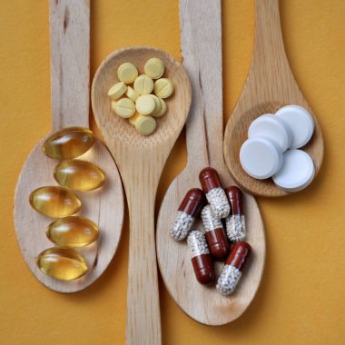 Tabletler, kapsüller, diyet takviyeleri, tahta kaşıklarda vitaminler. Tıbbi geçmiş