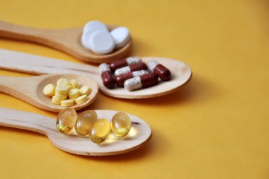 Tabletler, kapsüller, diyet takviyeleri, tahta kaşıklarda vitaminler. Tıbbi geçmiş