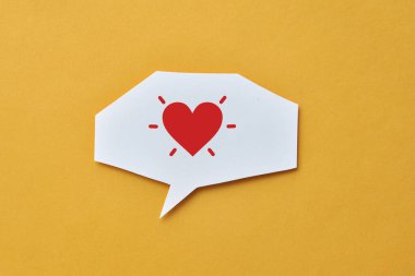 Konuşma balonunda kırmızı kağıt bir kalp. Aşkın sembolü, muhabbet ve aşk ilanı.