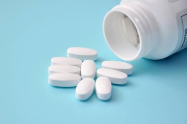 Mavi arka planda büyük beyaz haplar, tedavi ve sağlık arabası