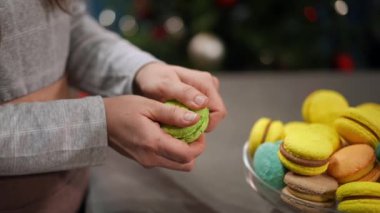Beyaz tereyağlı ve böğürtlenli yeşil Fransız kurabiyesi kıran genç bir kadının elleri. Tanınmayan beyaz kadın ağır çekimde lezzetli ev yapımı tatlıları gösteriyor.