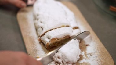 Yüksek açı, Noel pastasını yavaş çekimde masanda kesiyor. Bayram arifesinde evde lezzetli geleneksel hamur işleri gösteren beyaz bir kadın. Yeni yıl konsepti