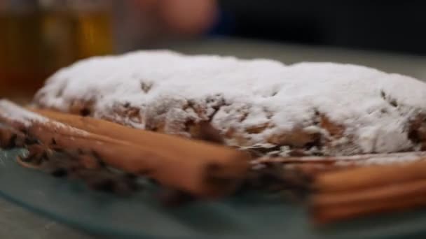 粉砂糖のトッピングとシナモンスティックがトレイに回転してクリスマスケーキを閉じます 屋内キッチンで大晦日のおいしい甘い伝統的なペストリー — ストック動画