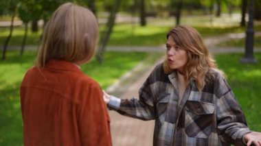 Ağır çekimde hareket eden, kızgın, tatminsiz bir kadın parkta arkadaşıyla tartışıyor. Tatmin olmamış, dışarıda kavga eden Kafkasyalı kadının portresi.