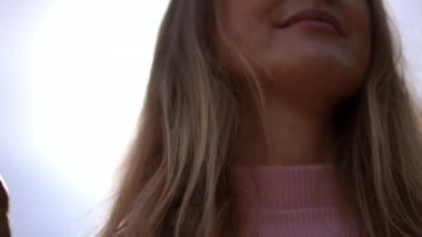 Yakın çekim, ince kadın eli, ağır çekimde esmer saçlara dokunuyor. Tanımlanamayan gülümseyen beyaz bir bayan güneşli havanın tadını çıkarıyor. Yaşam tarzı ve kadınlık kavramı