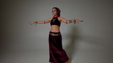 Ağır çekimde dans eden yetenekli dansçı göğüs ve kalça dansı yapıyor. Gri arka planda kendine güvenen beyaz kadının portresi. Koreografi ve sanat konsepti