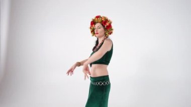 Canlı kamera, beyaz arka planda dans eden olgun ve güzel bir kadın olarak aşağı iniyor. Kafkasyalı dansçı Orta Doğu dansını yavaş çekimde yapıyor.