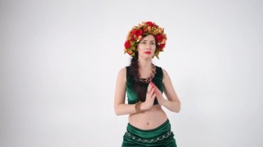 Kendine güvenen, el sıkışan, ağır çekimde Orta Doğu dansı yapan bir kadın. Beyaz arka planda dans eden beyaz tenli beyaz dansçının portresi.