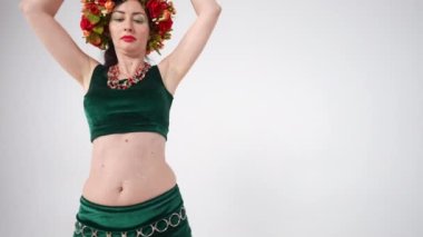 Zayıf, olgun bir kadın, kalçalarını yavaşça sallıyor ve beyaz arka planda göbek dansı yapıyor. Orta Doğu dansında kendinden emin beyaz bir dansçının arka plan portresi.