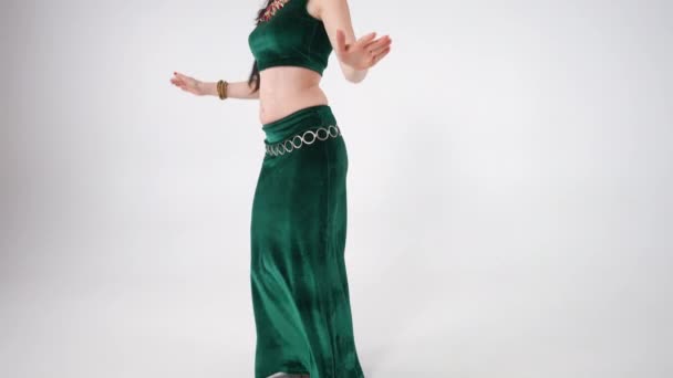 ゆっくりとした動きの中で腰を振りながらベリーダンスを披露するスリムな熟女としてライブカメラが動き出します 白を基調とした中東舞踊を踊る白人女性 — ストック動画